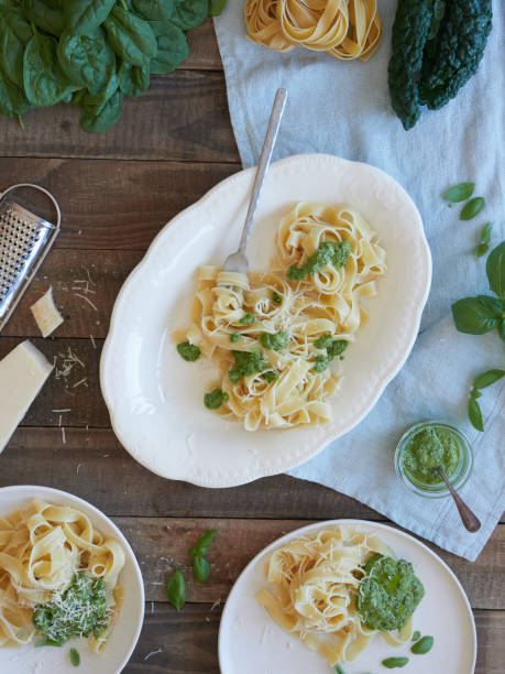 istock Composition of pasta on rustic wooden table, top view. Serving platter with tagliatelle and pesto sauce. Typical Italian food, parmesan cheese. 1881792880