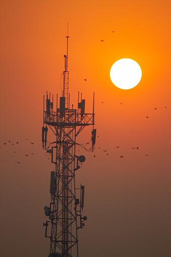 Golden sunrise illuminating a radio base station, with a bright sky in the background.