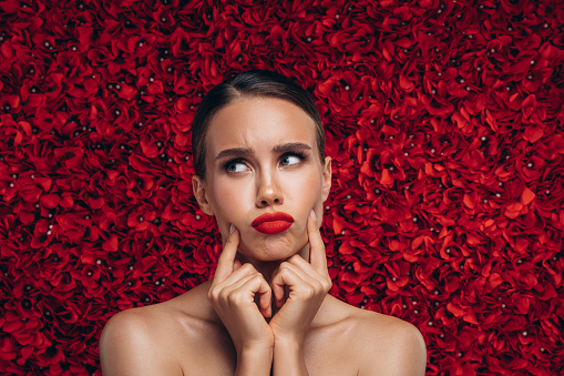 woman in pajamas colored rose gold With a red rose on the bed resting in the morning, Background concept, closeup flower.