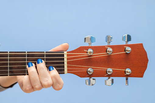 female fingers pinch the strings on a guitar. girl playing guitar. woman plucks a chord on a guitar, isolate