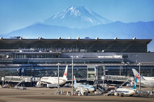 Tokyo, Japan - December 9, 2023: Aircraft from various airlines are seen at Terminal 3 of Haneda Airport, also known as the Tokyo International Airport, with Mount Fuji in the background.