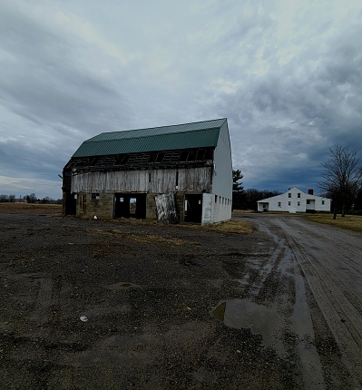 A weathered wooden barn stands against the vast open prairie on a stormy day in New Albany, Ohio