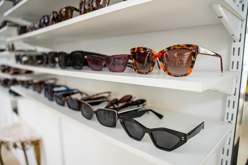 Shelves lined with various styles of sunglasses, showcasing modern optical trends suitable for diverse customers.
