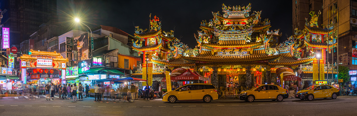 The ornate facade of Songshan Ciyou Temple beside the crowded pavements of Raohe Street Night Market in the heart of Taipei, Taiwan’s vibrant capital city.