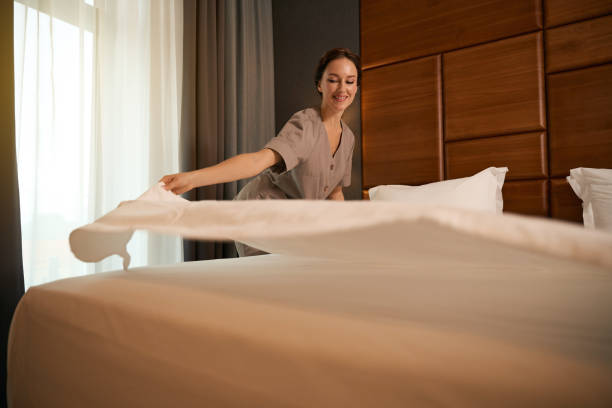 istock Joyous uniformed hotel maid is changing bedding in morning 1882030271