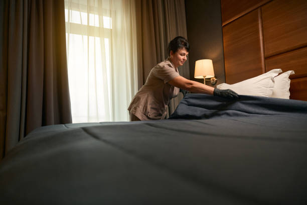 istock Uniformed maid performing in bed-making in guest suite 1882030368