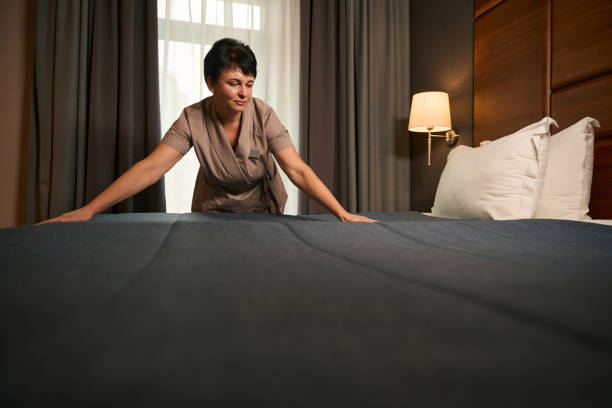 istock Maid dressed in uniform is making bed in hotel room 1882030407