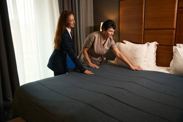 istock Maid making bed in guest suite under hotel manager supervision 1882030929