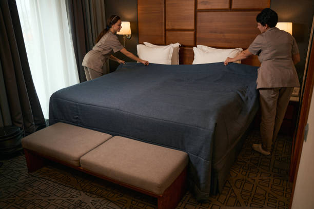 istock Team of maid service workers occupied with bed-making in suite 1882030954