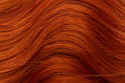 Red curly long hair close-up. A wave of hair as a background