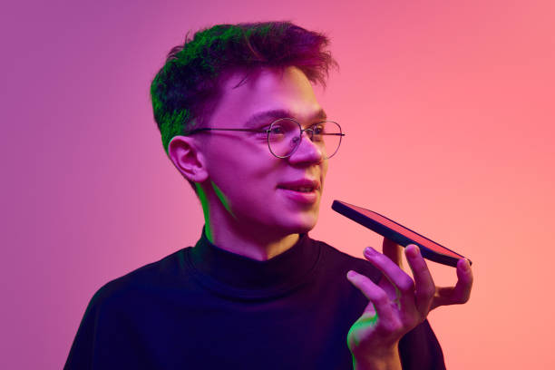 istock Smiling young man talking on mobile phone against gradient pink background in neon light. Online conversation 1882082220
