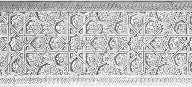 Geometric traditional Islamic ornament. Fragment of a carved mosaic on white marble. Abstract background.