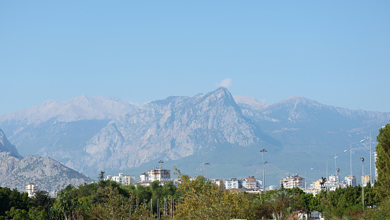 City landscape. Alley in the city park. On the horizon, the Ferris wheel and mountains in the haze. Turkey, Antalya.