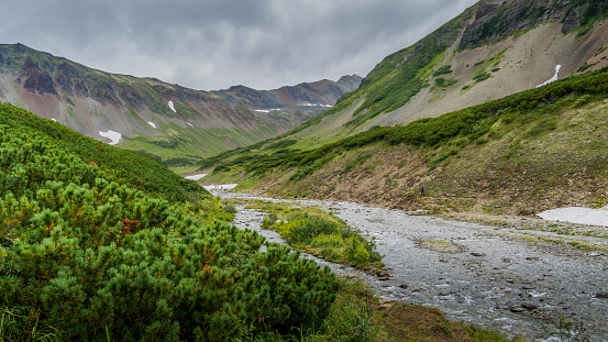 The scenic river goes through the Vachkazhets valley at Kamchatka krai, Russia, with beautiful mountains and grass fields around.