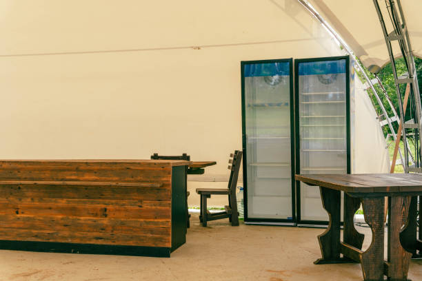 istock Visitors Tables, Soft Drink Coolers, and Wooden Table Counter in Empty Events Pavilion 1882199324