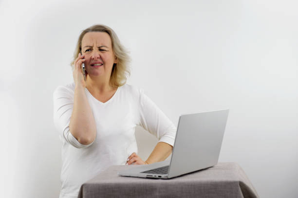 istock Puzzled worried freelance worker talking on mobile phone at home workplace, discussing problems, getting concerning news, bad connection, sitting at table with laptop at home 1882243170