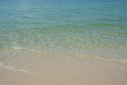 The sea is full of water lapping on the beautiful white sand beach.