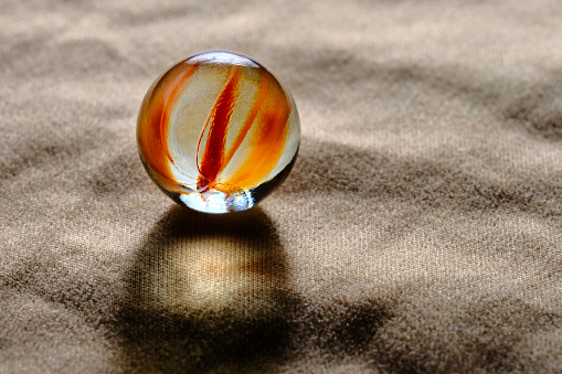 An orange colored marble over a cloth