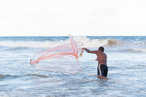 Salvador, Bahia, Brazil - April 26, 2019: Fisherman is seen throwing a net into the sea in the city of Salvador, Bahia.