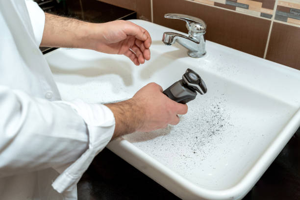 мужчина загрязняет раковину во время бритья с помощью электрической машины для камней - shaving equipment wash bowl bathroom razor стоковые фото и изображения