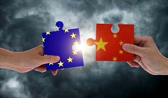 Hand holding European Union and China flags on puzzle pieces joining together
