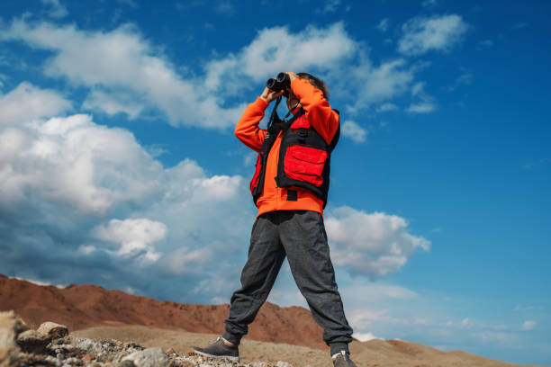 istock Boy tourist looking in binoculars in mountains 1882313347