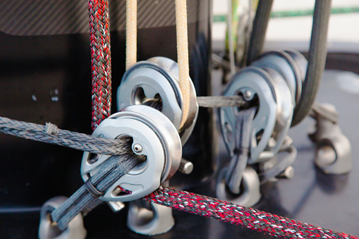 Part of the mast and hull of a sailing yacht, with multi-colored ropes, rollers and hinges for securing sails
