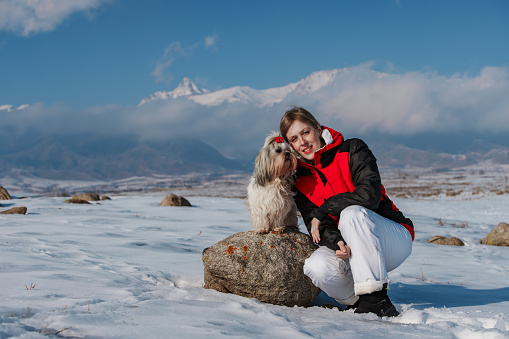 Young woman tourist with dog on winter mountains background