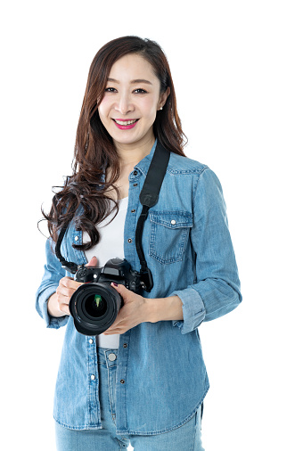 Woman holding professional digital camera on white background.