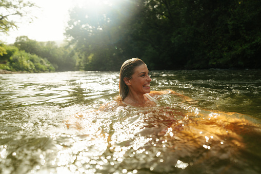 Photo of a beautiful woman soaking and swimming in the river alone.