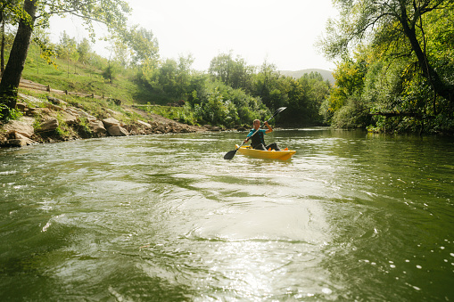 Photo of a young woman kayaking on the river.