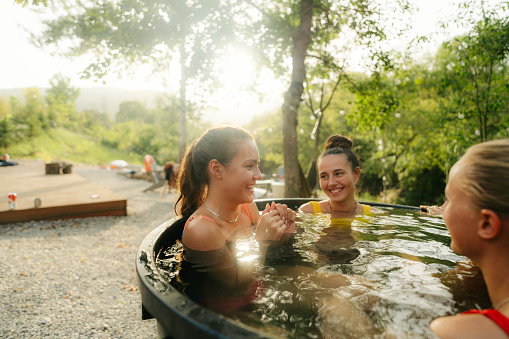 Photo of a young woman soaking in the garden tub with her friends.
