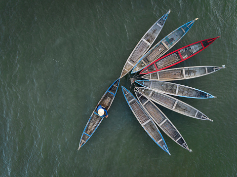 Drone view a woman is dragging and nailing wooden fishing boats, which made a flower shape on O Loan lagoon - Phu Yen province, central Vietnam