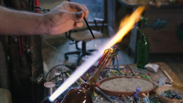 young man adds the eyes of a duck to a glass bottle he shaped like a duck