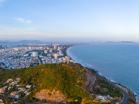 Panoramic coastal Vung Tau view from above, with waves, coastline, streets, coconut trees, Mount Nho in Vietnam behind the statue of Christ the King. Travel and landscape concept