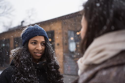 couple of young adult indian women talking oudtoors in winter snowy day