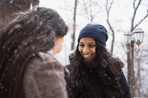 couple of young happy smiling women talking oudtoors walking in snowy day in winter park