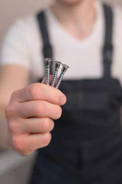 istock Furniture assembler holds countersunk screws in his hand, close-up. Construction concept, handyman 1882536448
