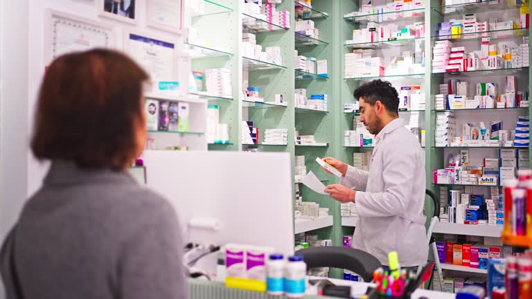 Adult woman buying medicine from a Male pharmacist while standing at the counter