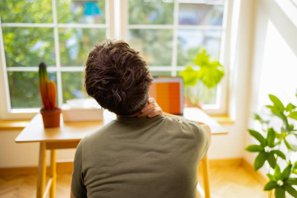 istock Male high school student experiencing a pain in shoulder, while e-learning at home 1882547475