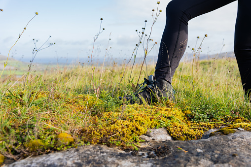 Close up of a hiker booted leg of a female traveler on the Irish peat and gray stone of a beautiful country landscape