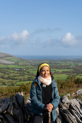 Smiling latin woman enjoying a splendid day in the middle of the nature of an Irish landscape with the sea and mountains in the background