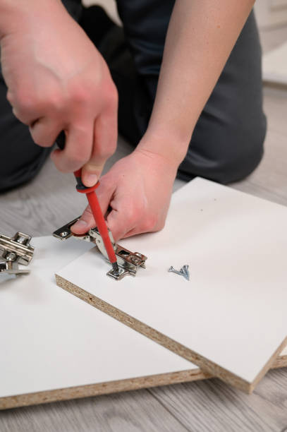 istock Furniture assembly. The worker inserts the loop and tightens it with a screwdriver. Adjustment of fittings, door hinges. 1882587342