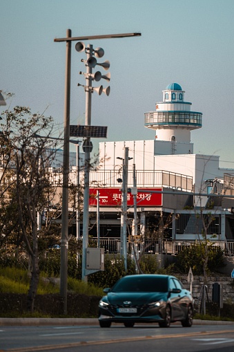 busan, South Korea – September 09, 2023: A car driving down the street next to a modern airport control tower in Busan, South Korea