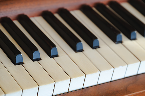 A closeup of the keys of an old vintage upright piano, worn out keyboard