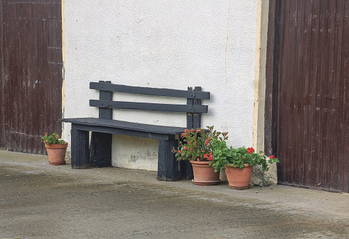 wooden bench on the wall of a farmhouse with some pots of plants on the sides