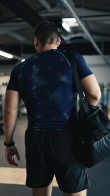 Muscular Male Athlete Picking Up Bag and Leaving Gym after Intense Workout