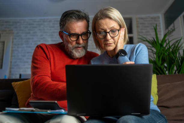 istock Serious couple sitting on couch in new home checking bills 1882763443