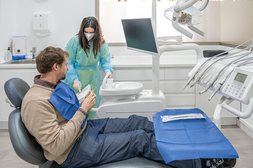A dental assistant helping a patient in a dental control with the consultation tools and protocol