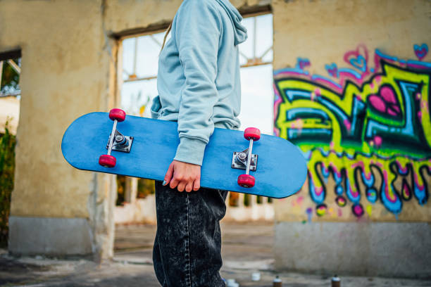 Woman with her skateboard standing in front of a wall with colorful graffiti